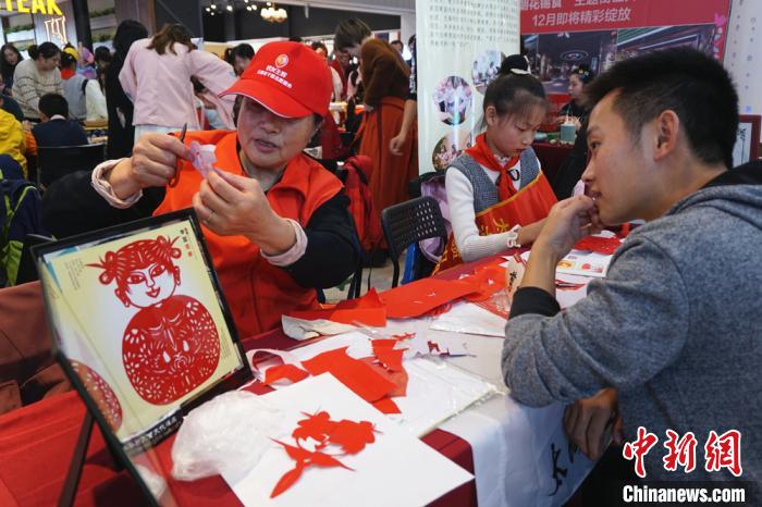 老师带着学生现场展示剪纸的技艺。　孙权 摄